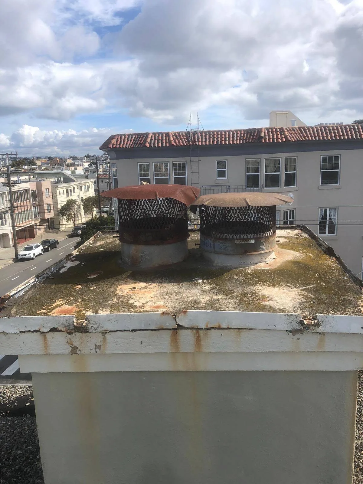 Two metal vent caps viewed from a residential rooftop